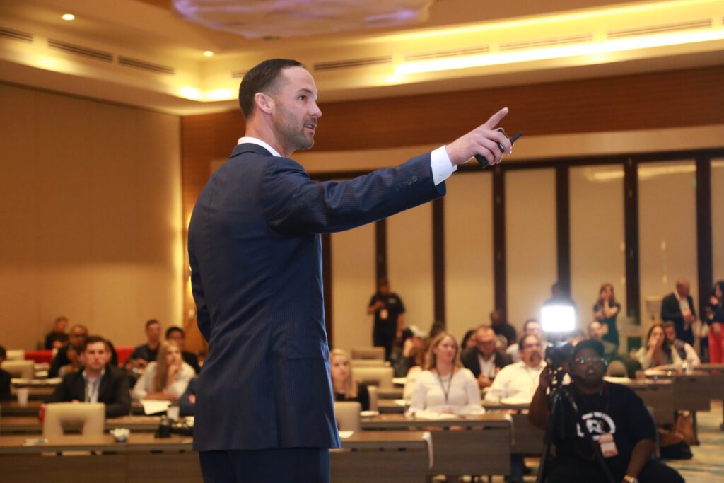 man in black suit standing on stage